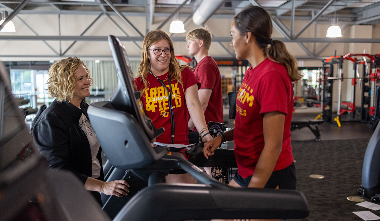 Professor Nicci Whalen works with students in the fitness center during May-Term class