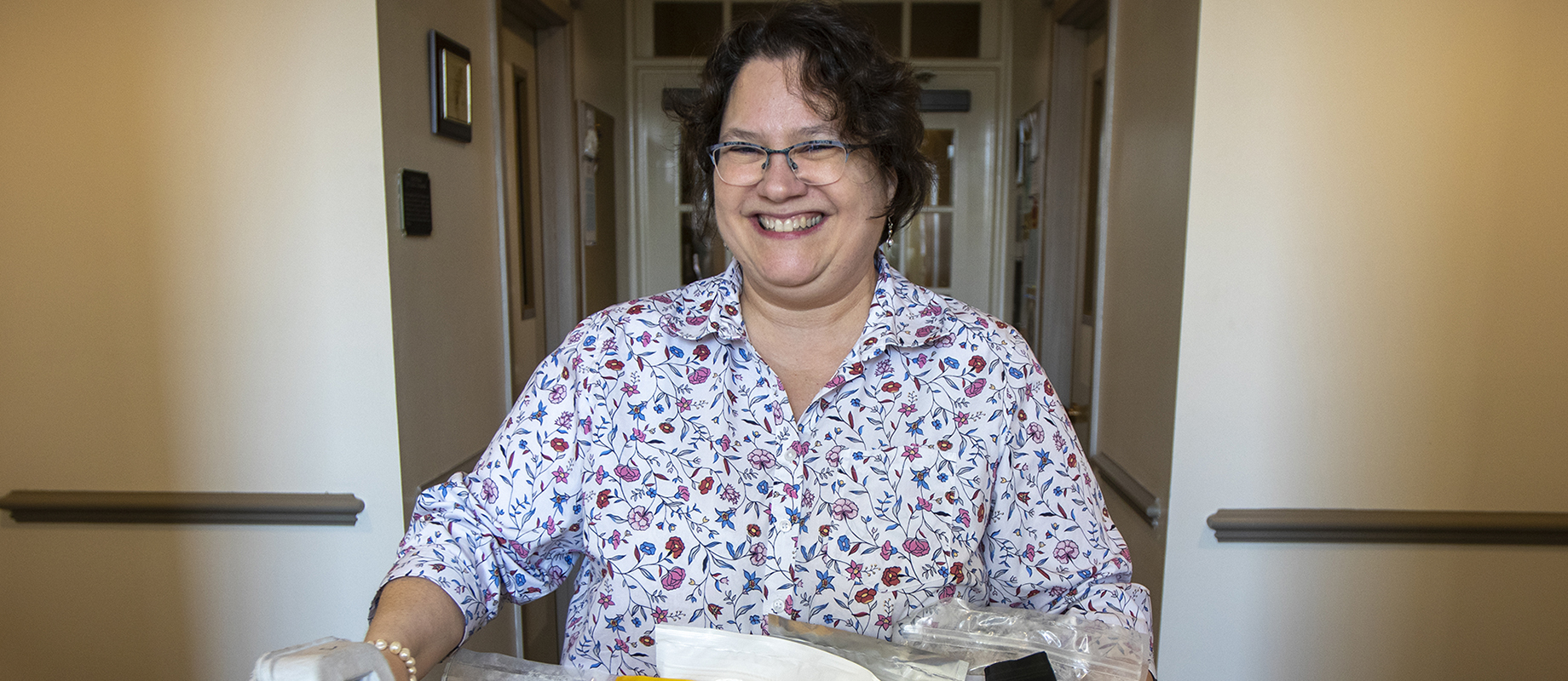 Simpson College professor CoryAnne Harrigan poses with a carton of food from the Iowa Food Cooperative.